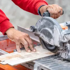 Mani esperte guidano una sega circolare per un preciso **taglio gres porcellanato**.