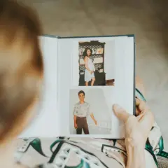 Osoba przegląda album ze zdjęciami, pokazujący ciążę i młodego mężczyznę. To inspiracja, jak zrobić album ze zdjęciami i opisami.