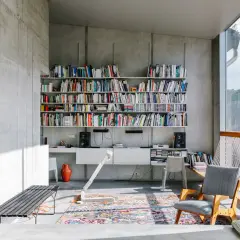 Ein bunter, detailreicher Perserteppich bildet einen warmen Kontrast zur kühlen Betonarchitektur und zeigt, wie man einen Perserteppich modern kombinieren kann.