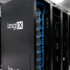 Des racks de serveurs noirs, dont un avec le logo "imgIX", remplis de câbles bleus et jaunes. C'est un peu ça, un serveur : le cœur de l'internet.
