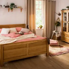 Przytulna sypialnia w stylu wiejskim z drewnianym łóżkiem, pastelową pościelą i szafą z przeszklonymi drzwiczkami.