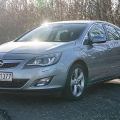 Szary Opel Astra J na drodze. Opis przycisków w tym modelu jest kluczowy dla komfortowej jazdy.