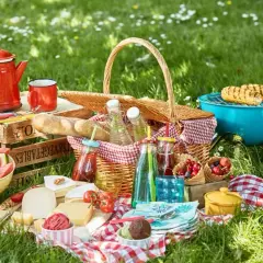 Idealne jedzenie na piknik: kosz pełen smakołyków, grillowana kukurydza, sery, owoce i napoje.