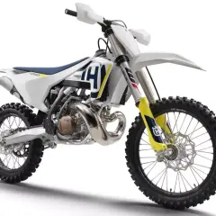 Nowy motocykl cross Husqvarna 250 gotowy na wyzwania toru. Biało-niebiesko-żółte malowanie, potężny silnik i terenowe opony.