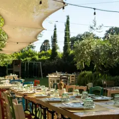 Tavoli apparecchiati all'aperto in un giardino lussureggiante, un'atmosfera perfetta per scoprire i migliori ristoranti a Firenze.