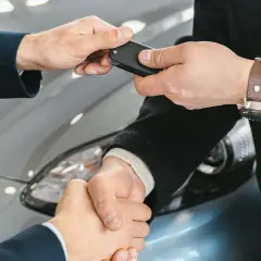 Przekazanie kluczyków do auta i uścisk dłoni. Transakcja kupna auta bez OC zakończona sukcesem.