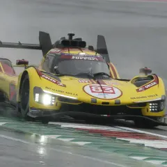 Żółty bolid Ferrari z numerem 83 na torze podczas deszczowego wyścigu 24h Le Mans.