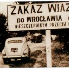 Znak "Zakaz wjazdu do Wrocławia osobom nieszczepionym przeciw ospie". W tle samochód i drzewa.