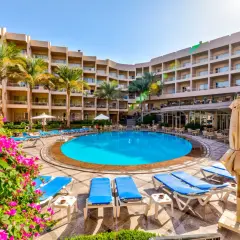 Basen hotelowy Beau Rivage z leżakami i palmami, otoczony budynkami hotelowymi.