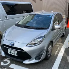Srebrny samochód na parkingu w Japonii, gdzie obowiązuje ruch lewostronny. Obok stoi srebrny van.