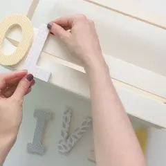 Manos decorando letras para manualidades de comunión, creando un detalle personal para un día especial.