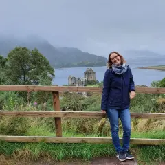 Frau vor schottischer Burg bei typischem Septemberwetter. Die Landschaft ist neblig, aber die Stimmung ist fröhlich.