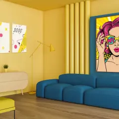 Żółte ściany, niebieska kanapa i kolorowe plakaty pop art tworzą energetyczne wnętrze.
