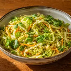 En skål med asiatisk kålsallad med strimlad kål, morötter, koriander och sesamfrön.
