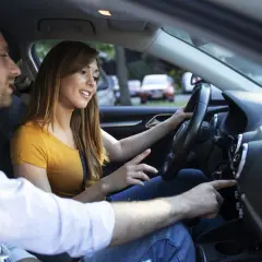 Un jeune couple discute en voiture. Elle conduit, il lui montre quelque chose sur le tableau de bord. La conduite accompagnée 3000 km en combien de temps ?
