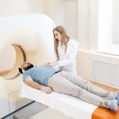 Pacjent leży na stole do rezonansu magnetycznego, pielęgniarka przygotowuje go do badania. Zastanawiasz się, ile się czeka na wynik rezonansu z kontrastem?