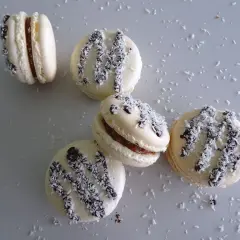 Macarons à la ganache coco, parsemés de noix de coco râpée et de copeaux de chocolat noir.