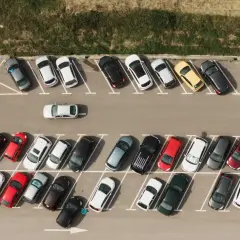 Widok z góry na parking z samochodami. Widać jak prawidłowo wykonać parkowanie skośne kiedy skręcać.