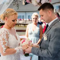 Para młoda wymienia obrączki podczas ceremonii ślubu konkordatowego. Dokumenty ślubne czekają na podpisanie.