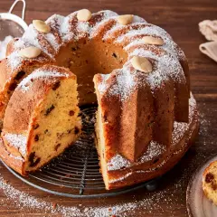 Ein köstlicher Gugelhupf-Kuchen mit Rosinen und Mandeln, bestäubt mit Puderzucker. Der Gugelhupf-Kuchen geht nicht aus der Form, aber ein Stück wurde bereits herausgeschnitten.