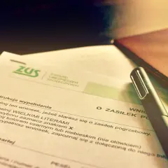 Wniosek o zasiłek pogrzebowy ZUS. Dokumenty i długopis na biurku sugerują formalności związane ze śmiercią za granicą.