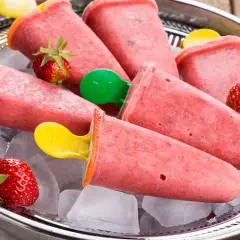 Erfrischendes Erdbeer-Eis am Stiel selber machen. Auf einem Silbertablett mit Eiswürfeln und frischen Erdbeeren serviert.