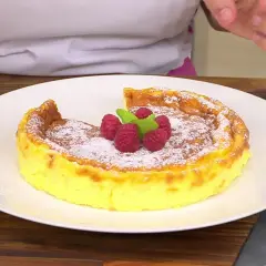 Tarta de queso Eva Arguiñano, dorada y espolvoreada con azúcar glas, coronada con frambuesas y menta. ¡Un postre irresistible!