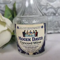 Butelka wina Mogen David Concord Wine z etykietą i białym kwiatem w tle.