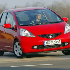 Czerwony Honda Jazz z młodym kierowcą za kierownicą. Wiele osób szuka honda jazz opinie przed zakupem.
