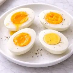 Quatre moitiés d'œufs durs sur une assiette blanche, certains avec un jaune coulant. Le temps d'un œuf parfait.