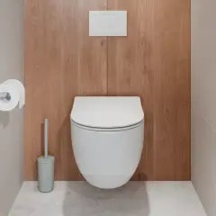 Uchwyt na papier toaletowy zamontowany na wysokości ok. 65 cm od podłogi, obok nowoczesnej toalety.