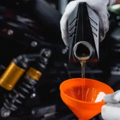 Olej 10w40 do jakich silników? Wlewanie oleju do motocykla przez pomarańczowy lejek.