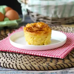En gyllene, krispig makaronipudding på en vit tallrik, perfekt för ett maskros recept. Ägg i bakgrunden.