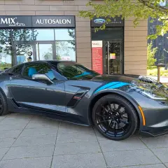 Szary Chevrolet Corvette C7 z niebieskimi pasami, zaparkowany przed salonem samochodowym. Sprawdź aktualną corvette c7 cena!