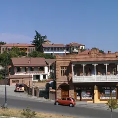 Urokliwe uliczki Telavi, Gruzja, z tradycyjną architekturą i balkonami. Pomarańczowy samochód jedzie po drodze.