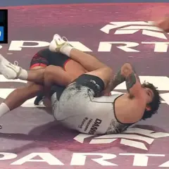 Intens kamp i catch wrestling. En brottare har den andra i ett grepp på mattan.