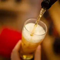 Z butelki leje się złociste piwo Peroni do szklanki, tworząc obfitą pianę.