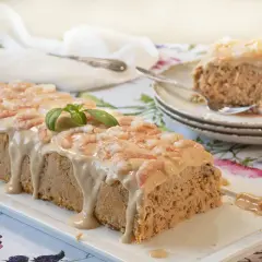 Pastel de pescado al horno cubierto con salsa cremosa y camarones. Una rebanada ya servida en un plato.