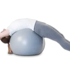 Une femme s'étire sur un ballon de gym, le dos cambré, dans une posture qui pourrait aider à corriger une cyphose.