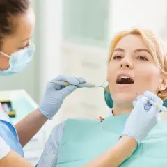 Dentystka bada zęby pacjentki narzędziami stomatologicznymi.