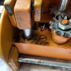 Zbliżenie na mechanizm zębatkowy pomarańczowego lewarka z widocznymi śladami oleju.