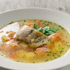 Aksamitna, aromatyczna najlepsza zupa rybna z kawałkami ryby, ziemniakami i marchewką, ozdobiona natką pietruszki.
