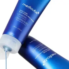 Två blå tuber med Medicube Zero Pore Blackhead Mud Mask. En tub har en öppen kork där masken droppar ut, en lösning för oljig hy orsak.