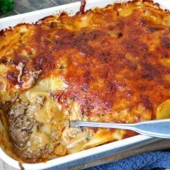 Herzhafter kartoffelauflauf mit Hackfleisch, überbacken mit goldbraunem Käse. Eine Gabel steckt in der dampfenden Schüssel.