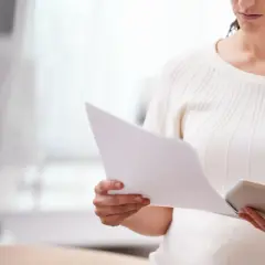 Kobieta analizuje dokumenty, zastanawiając się, czy można przełożyć sprawę w sądzie.