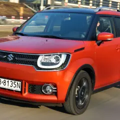 Pomarańczowy Suzuki Ignis z czarnym dachem pędzi po drodze. Kierowca w środku.