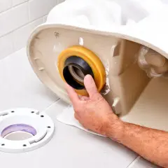 Hand installing a wax ring onto the base of a toilet, preventing a toilet leaking at base.