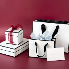 Vita presentaskar och påsar med svarta band. En presentinslagning påse med silkespapper och ett kort med texten "something special".