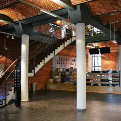 Wnętrze muzeum sztuki współczesnej z ceglanymi ścianami, łukowym sufitem i schodami.