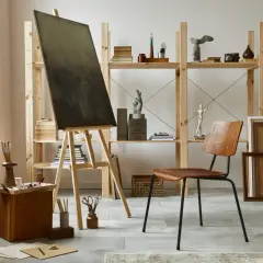 An art studio aesthetic with a canvas on an easel, wooden furniture, sculptures, and art supplies.